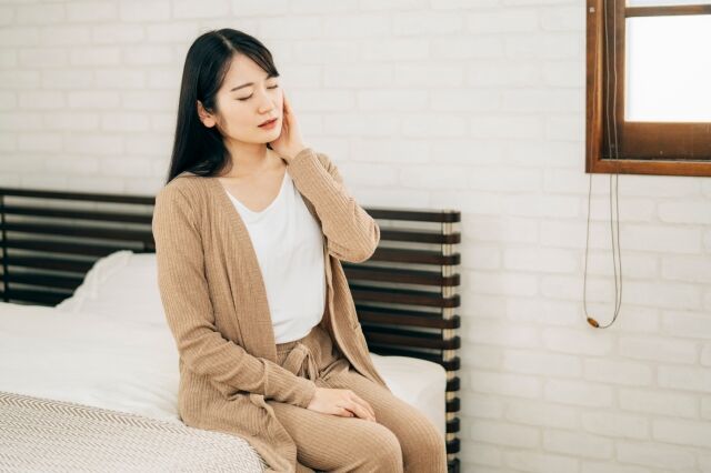 ベッドで肩を押える女性